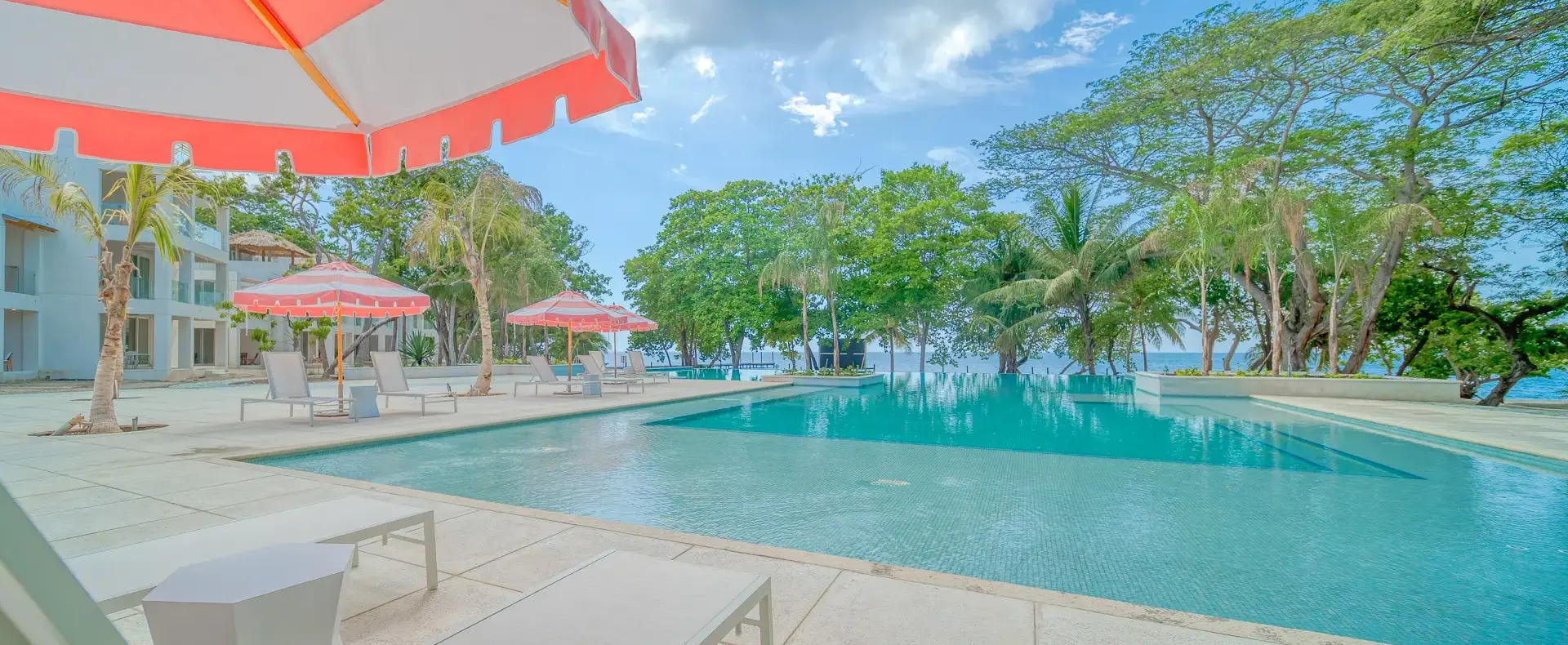 Pool with beach umbrellas at Watercolors D4 condo, West Bay, Roatan