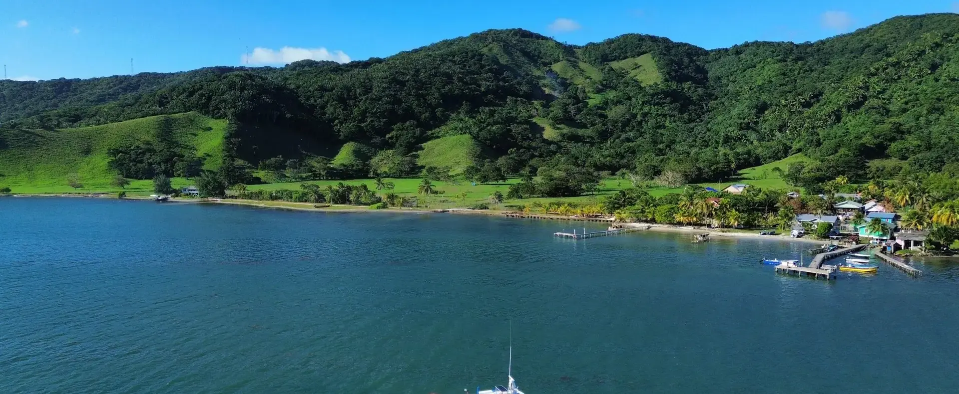 Boat in a quiet Guanaja bay below green mountains