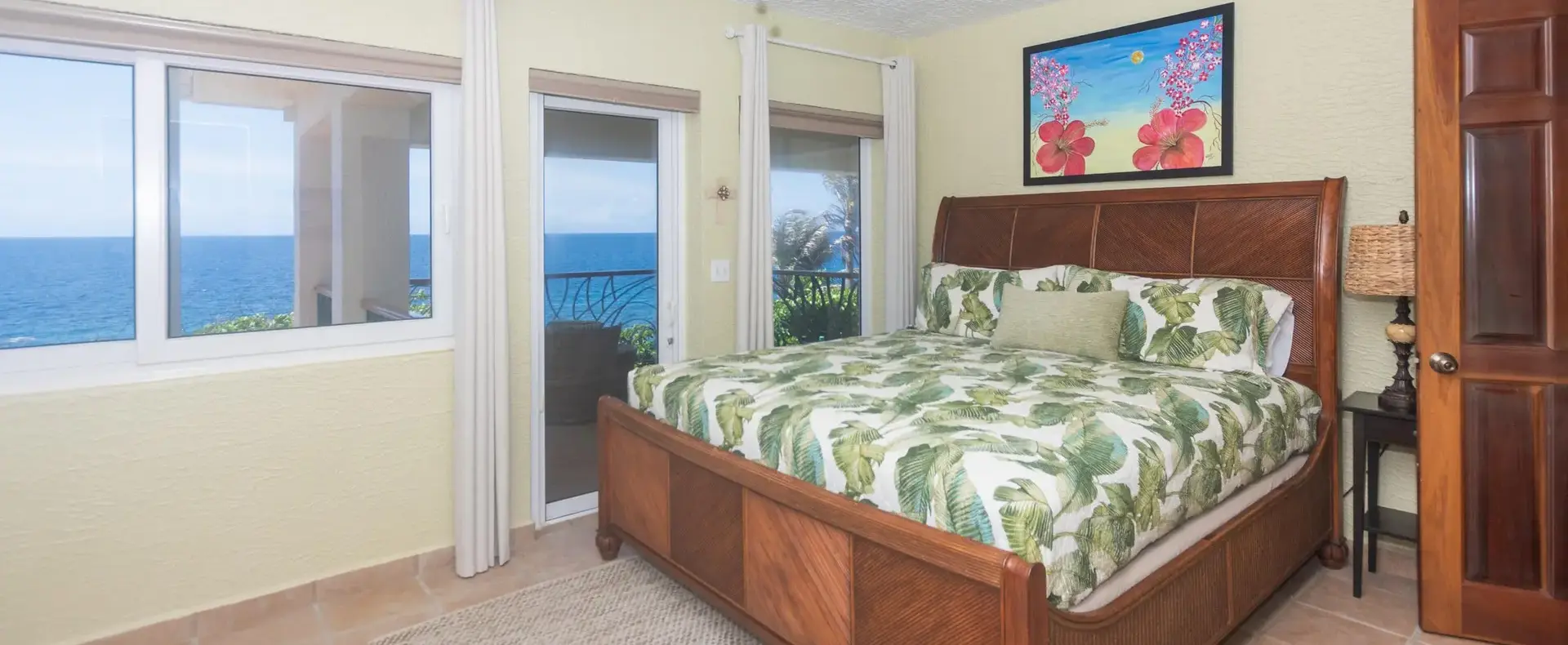 Guest bedroom with tropical bedding and ocean-view windows