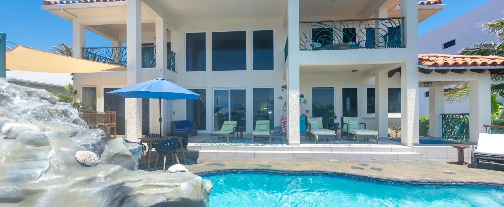 Free-form pool with natural rock waterfall in front of Casa Cascada, an oceanfront home in Lighthouse Estates, Roatan